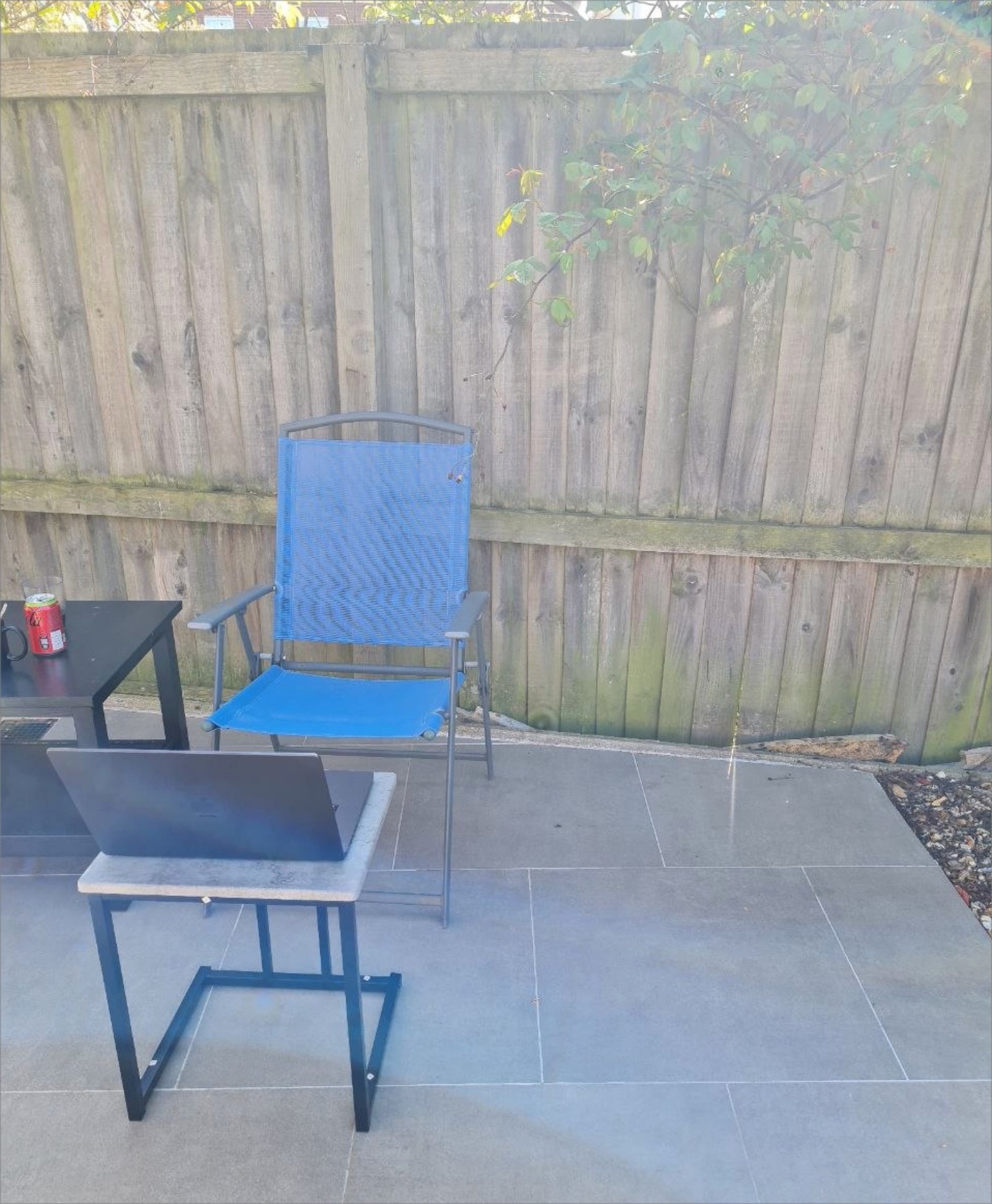 The outdoor workshop: laptop on a side table, chair, and the test fence in the background